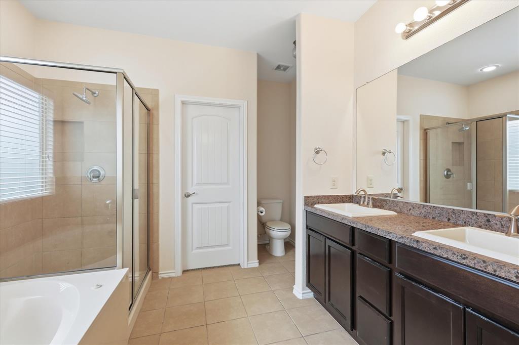 720 Rio Bravo Drive Fort Worth, TX 76052 - Photo 22 of 38 Bathroom featuring a dual vanity with dark wood cabinetry, a large frameless mirror, and a combination shower-tub unit with a glass enclosure