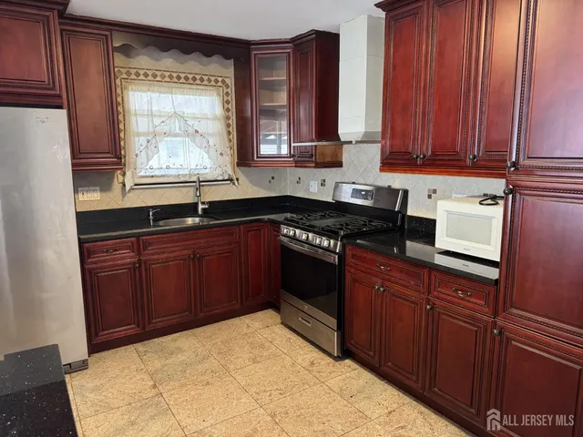 a kitchen with stainless steel appliances granite countertop wooden cabinets a sink and a stove
