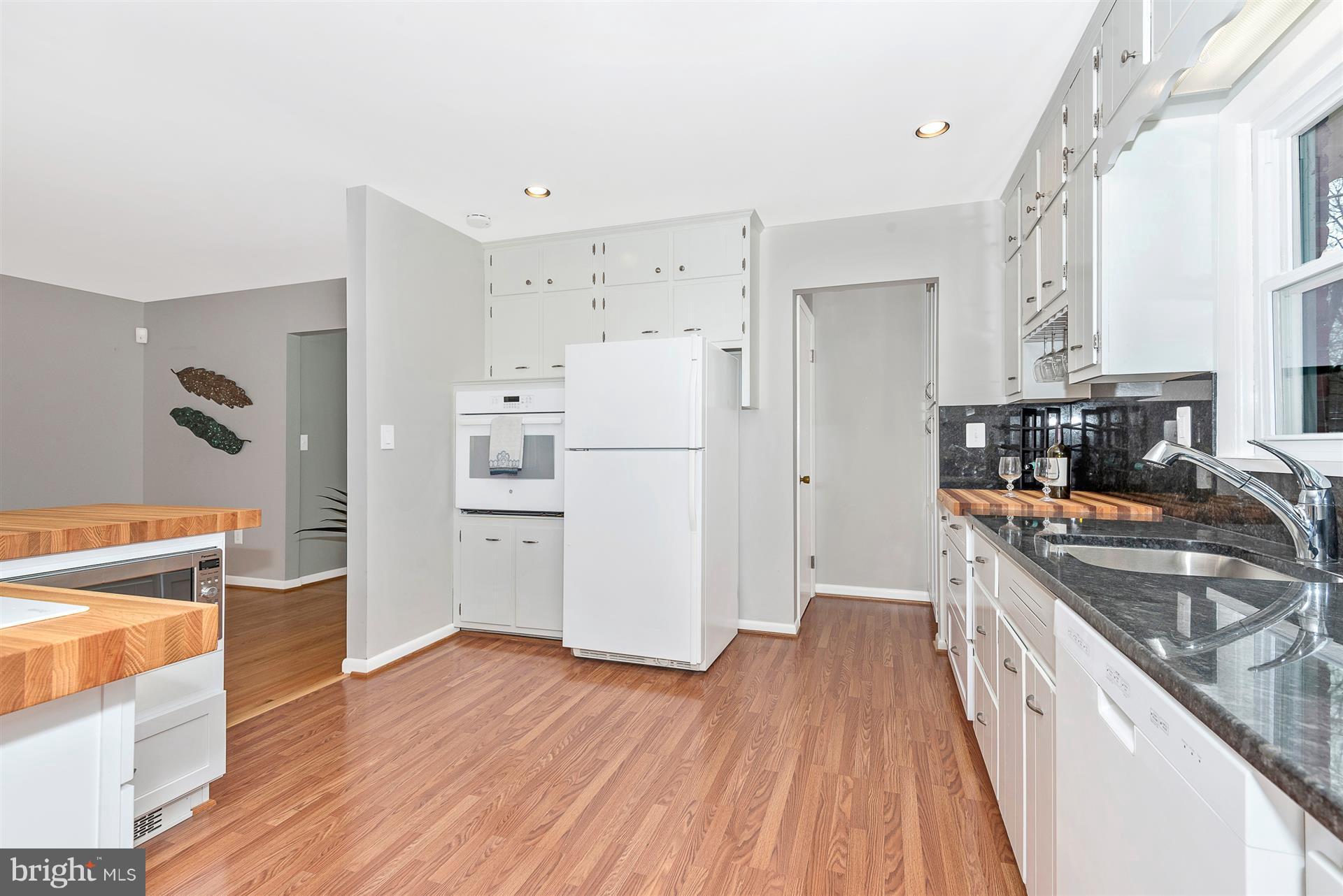 9416 Emory Grove Road Gaithersburg, MD 20877 - Photo 13 of 30 a kitchen with stainless steel appliances a refrigerator a stove a sink and white cabinets with wooden floor