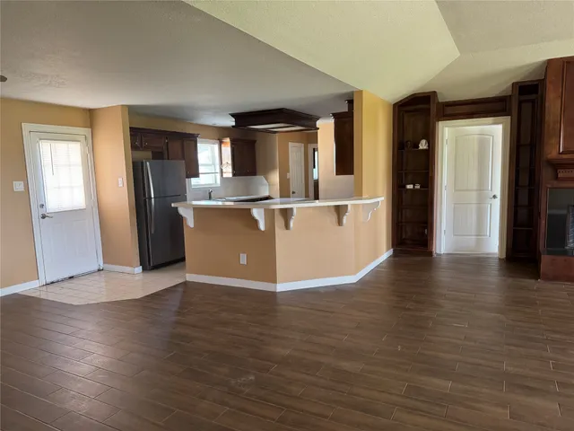 a view of a kitchen with kitchen island wooden floors and stainless steel appliances