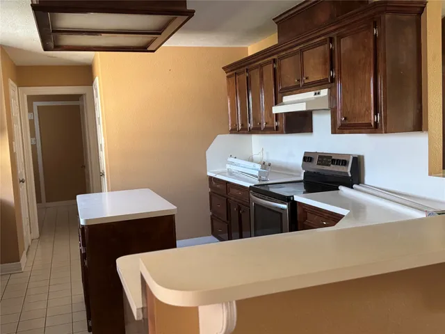 a kitchen with granite countertop a sink a stove and refrigerator