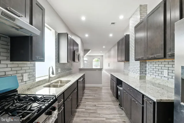 a kitchen with stainless steel appliances granite countertop a sink stove and cabinets