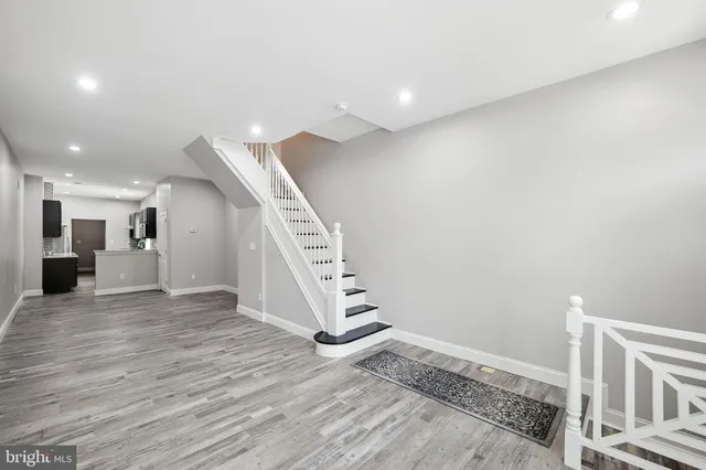 a view of an empty room with wooden floor and stairs