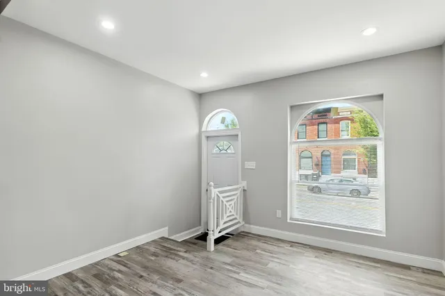 an empty room with wooden floor cabinet and windows