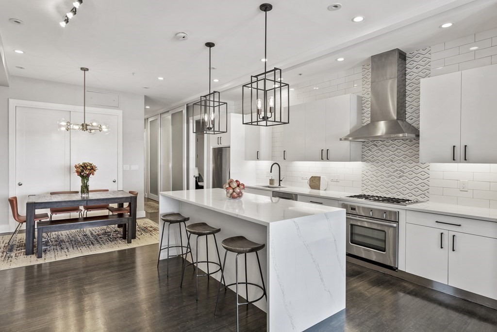 a kitchen with stainless steel appliances a kitchen island a stove a table and chairs in it