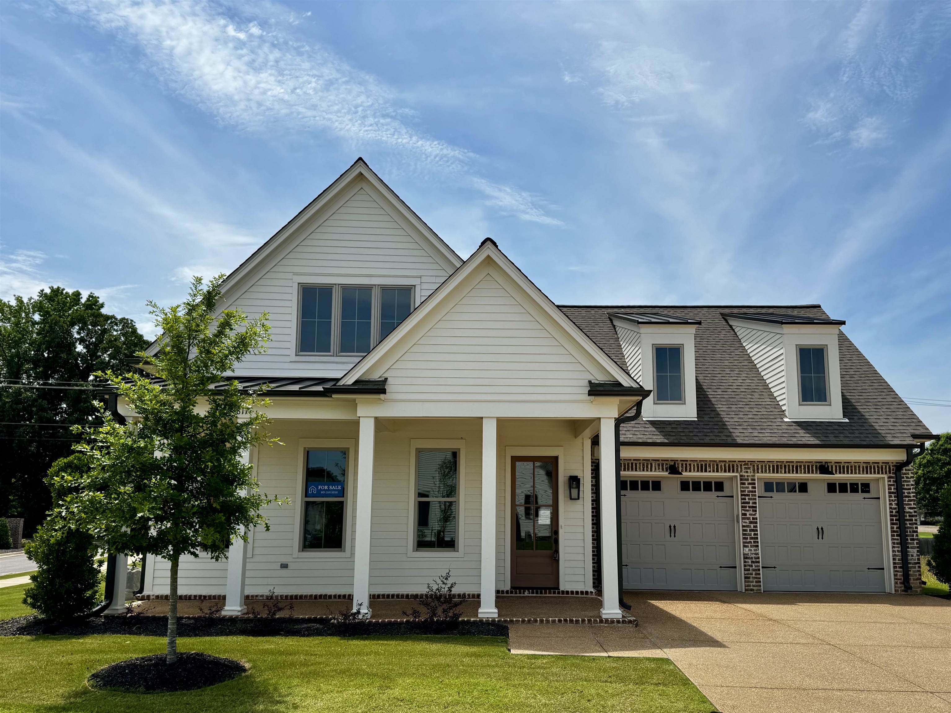 View of front of home with concrete driveway, covered porch, a front yard, and a shingled roof