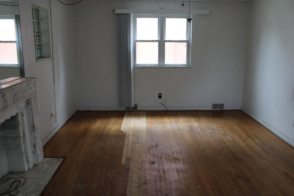 825 Liberty Street Duquesne, PA 15110 - Photo 4 of 25 an empty room with wooden floor and windows with curtains
