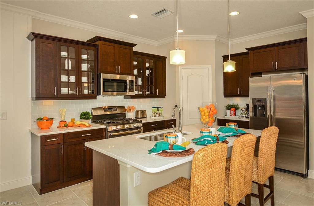 4665 Centaurus Circle Naples, FL 34120 - Photo 4 of 16 a kitchen with stainless steel appliances a sink a stove a refrigerator cabinets and a dining table
