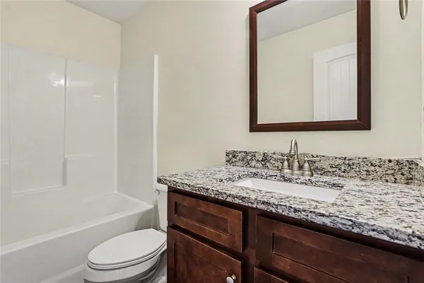 a bathroom with a granite countertop sink a toilet and bathtub
