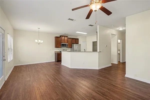 a view of a kitchen with a sink a refrigerator a ceiling fan and wooden floor
