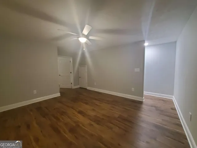 an empty room with wooden floor and fan