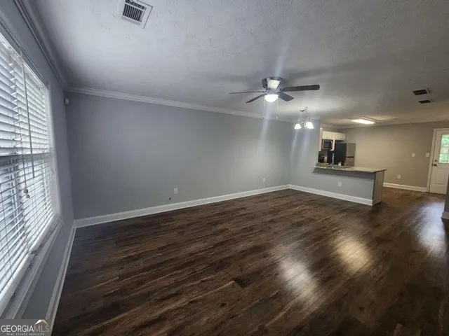 an empty room with wooden floor ceiling fan and windows