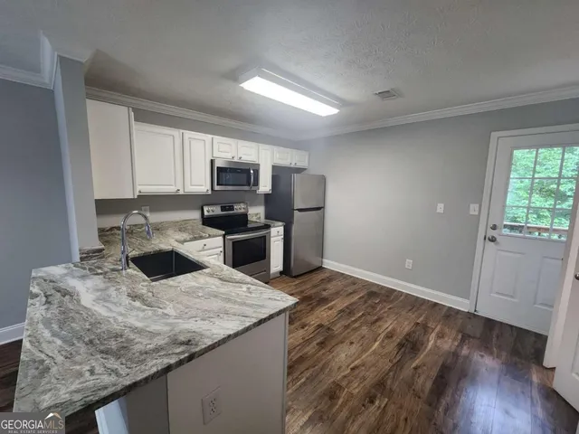 a kitchen with granite countertop a sink stove and refrigerator