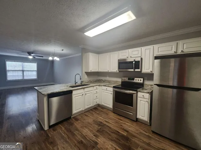 a kitchen with granite countertop a refrigerator stove top oven and sink