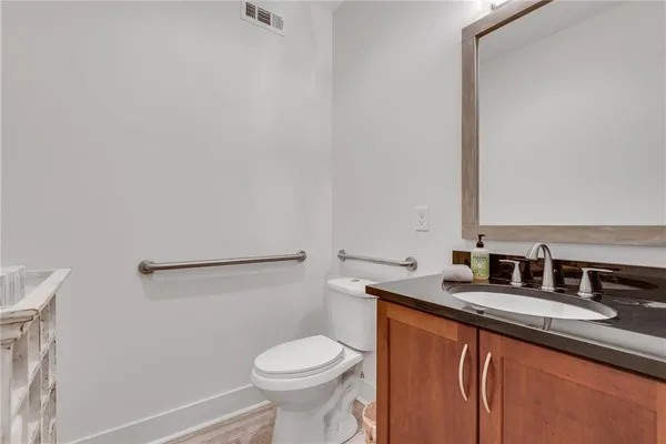 a bathroom with a granite countertop sink and a toilet