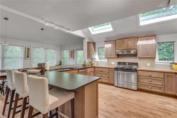 a kitchen with stainless steel appliances granite countertop a stove a sink dishwasher a stove and a refrigerator with wooden floor