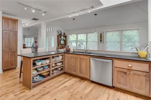 a kitchen with stainless steel appliances granite countertop a sink a stove cabinets and wooden floor