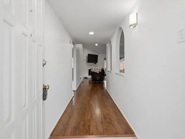 a view of a hallway with wooden floor and a bathroom