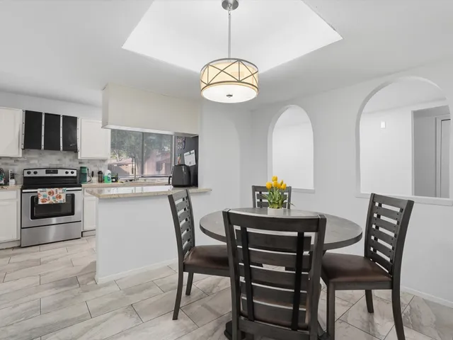 a dining room with wooden floor a chandelier a wooden table and chairs