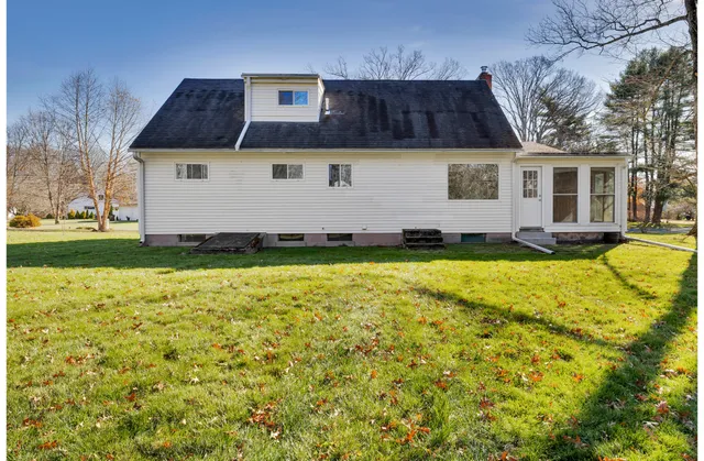 a front view of house with yard and trees in the background