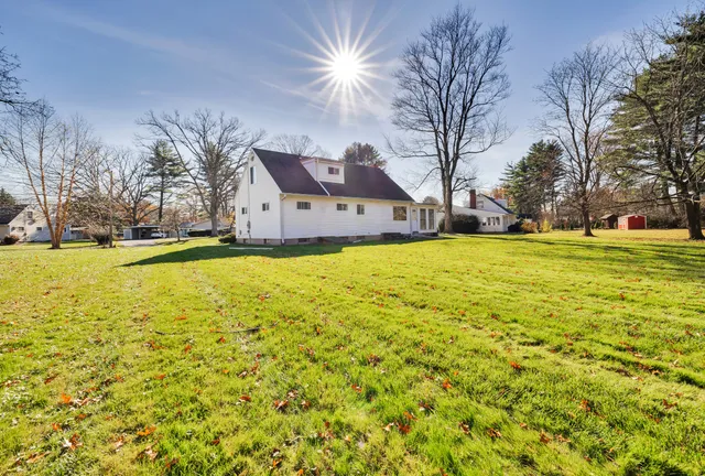 a view of a large pool with lawn chairs under an umbrella