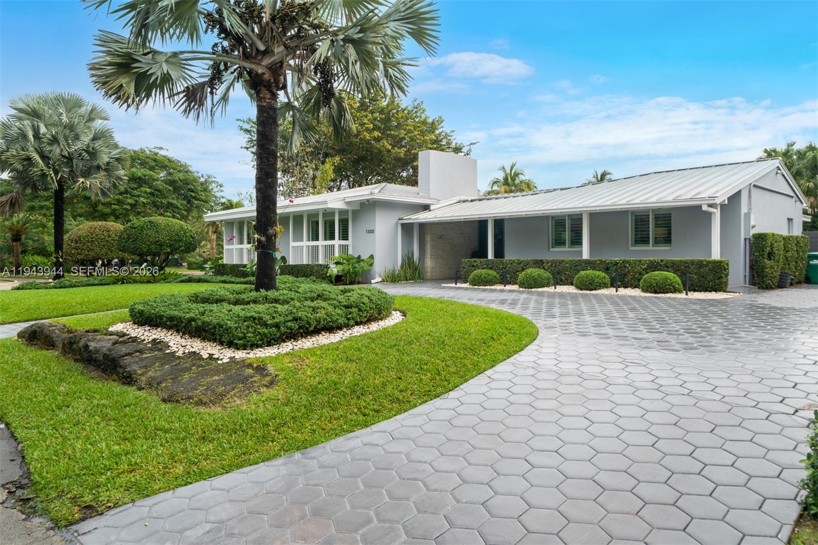 13333 Southwest 59th Court Pinecrest, FL 33156 - Photo 2 of 16 a front view of a house with a yard and potted plants