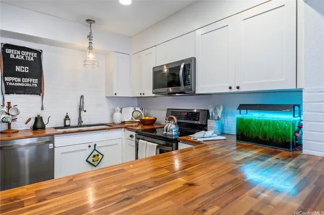 a kitchen with stainless steel appliances a sink cabinets and a wooden floor