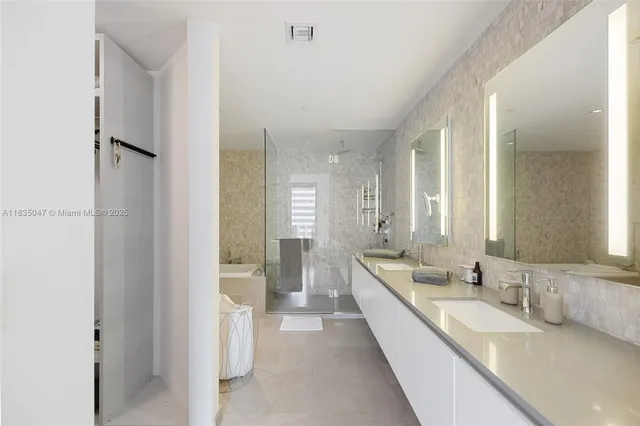 a large en suite bathroom with a double vanity sink a mirror and a bathtub