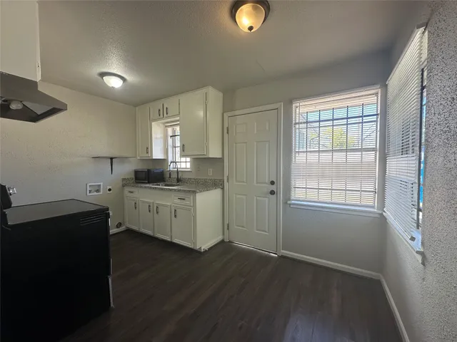 a kitchen with granite countertop a sink cabinets and wooden floor