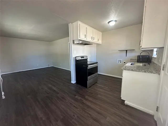 a kitchen with wooden floor and steel appliances