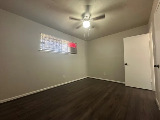 an empty room with wooden floor and fan