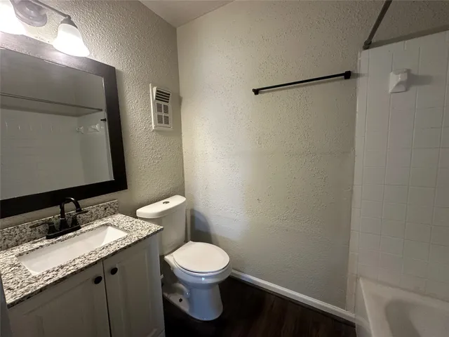 a bathroom with a granite countertop sink toilet and a mirror