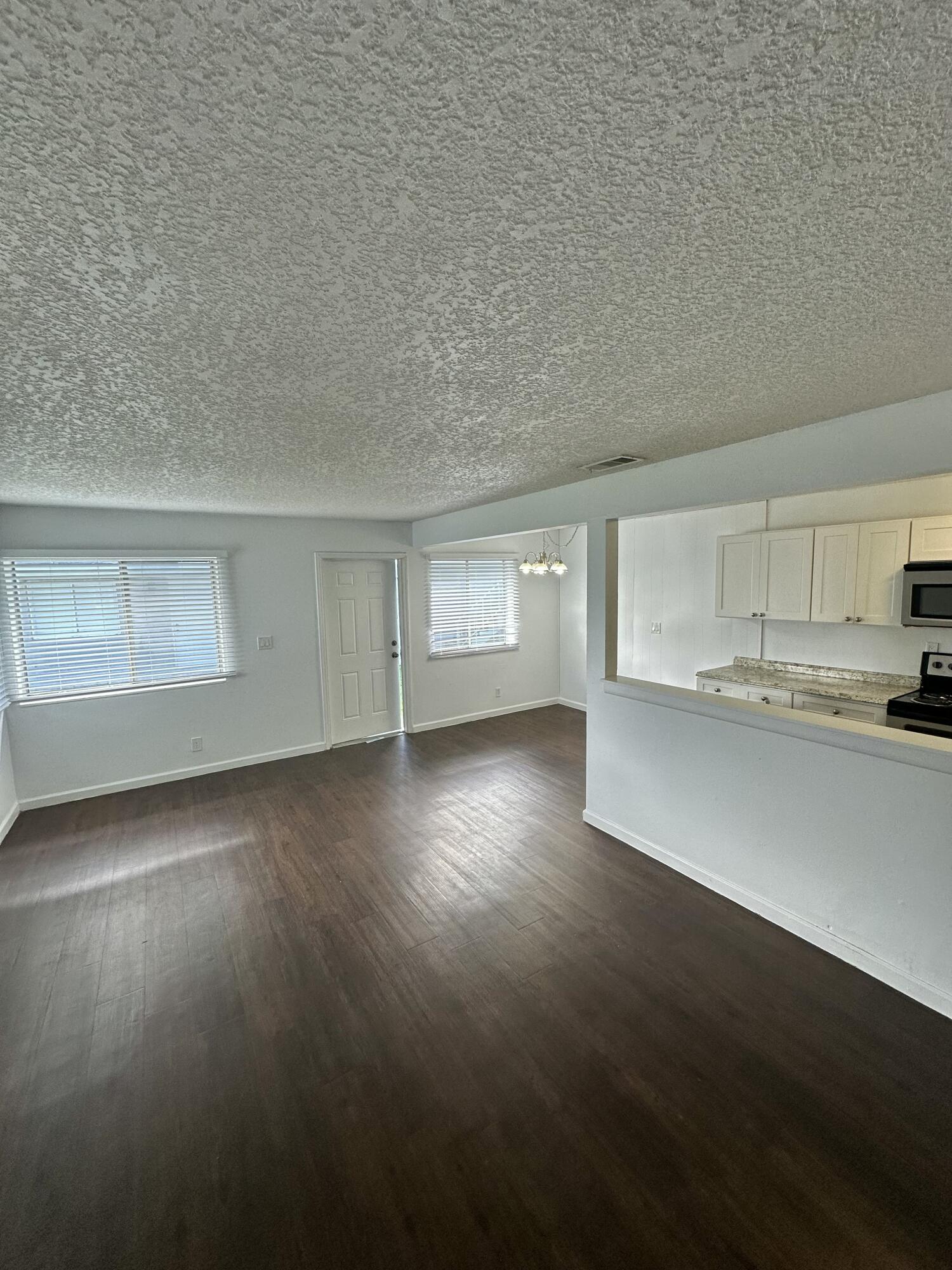 108 East Tiffany Drive, Unit 2 West Palm Beach, FL 33407 - Photo 6 of 14 a view of empty room with wooden floor and kitchen