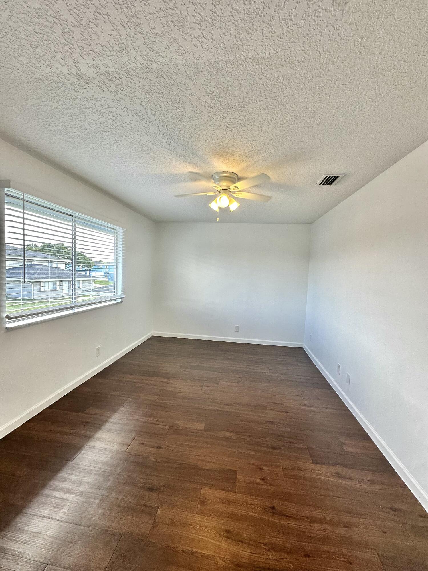 108 East Tiffany Drive, Unit 2 West Palm Beach, FL 33407 - Photo 9 of 14 an empty room with wooden floor and windows