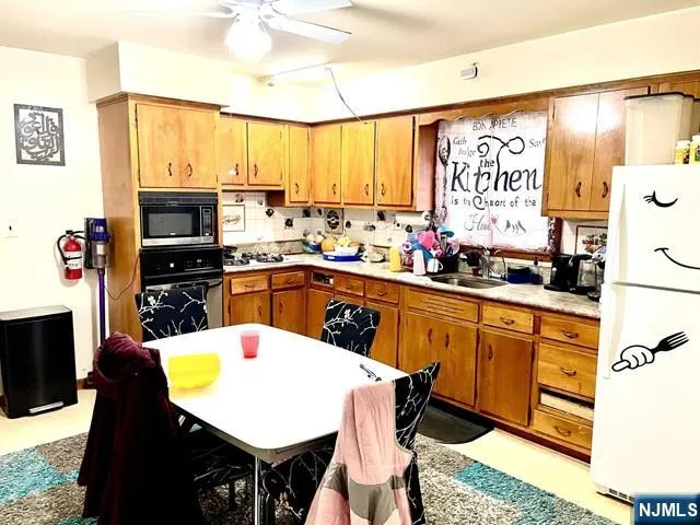 a kitchen with stainless steel appliances a sink a stove a refrigerator cabinets and a dining table