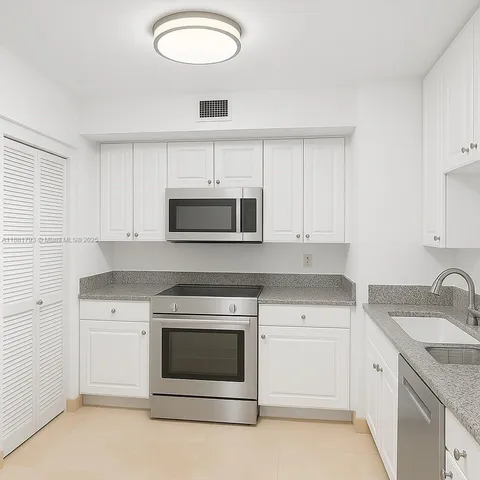 a kitchen with granite countertop white cabinets and sink