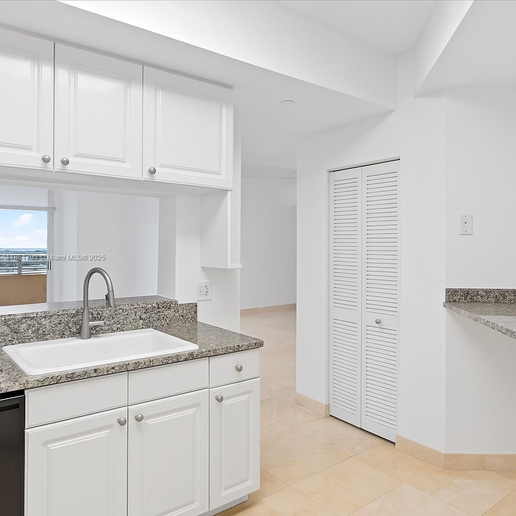 888 Brickell Key Drive, Unit 2510 Miami, FL 33131 - Photo 21 of 22 a kitchen with granite countertop white cabinets and sink