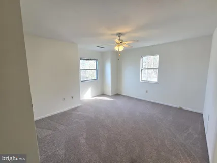 a view of empty room with windows and chandelier fan