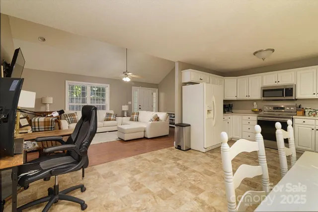 a living room with furniture a flat screen tv and a refrigerator