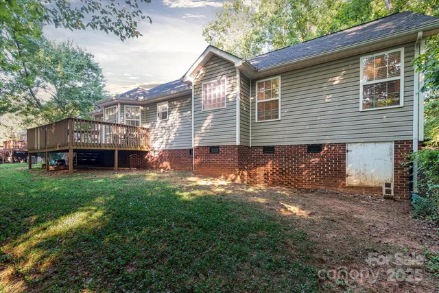 a backyard of a house with wooden deck table and chairs