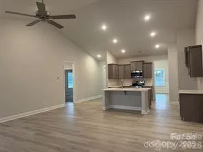 a large kitchen with stainless steel appliances a large counter top and wooden floor
