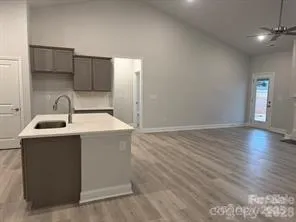 a kitchen with kitchen island a sink wooden floor and entryway