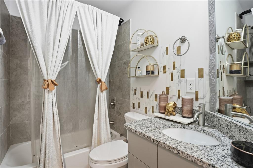 5663 Eternal Drive Atlanta, GA 30349 - Photo 25 of 37 a bathroom with a granite countertop sink toilet and shower