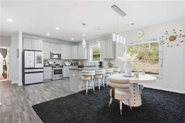 a kitchen with a dining table chairs stove refrigerator and cabinets