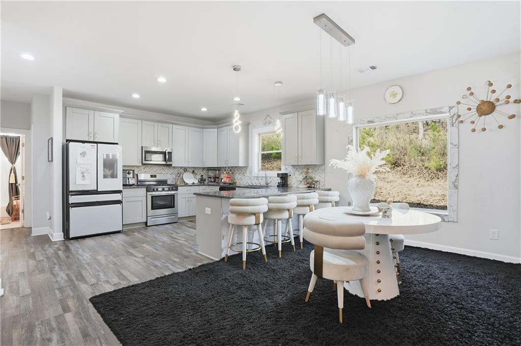 5663 Eternal Drive Atlanta, GA 30349 - Photo 8 of 37 a kitchen with a dining table chairs stove refrigerator and cabinets