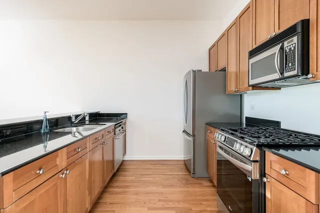 a kitchen with granite countertop a sink stove and microwave