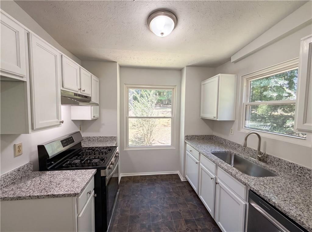 6830 Earlhurst Road Atlanta, GA 30349 - Photo 8 of 27 a kitchen with granite countertop a sink stove and cabinets