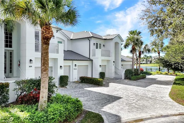 a view of a white house with a yard and potted plants