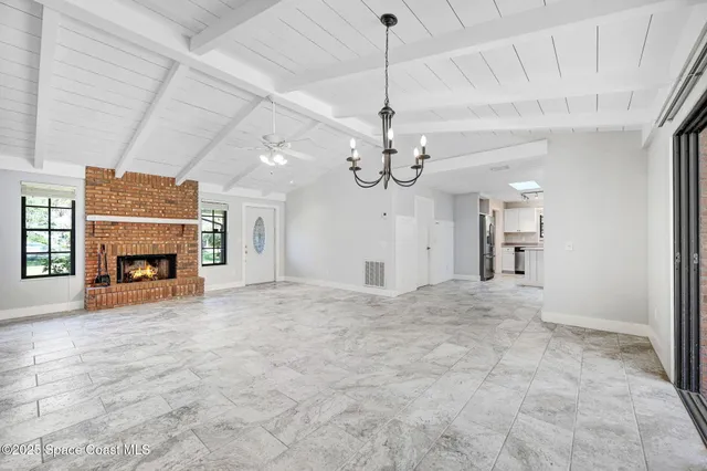 a view of a livingroom with a fireplace a chandelier and stairs
