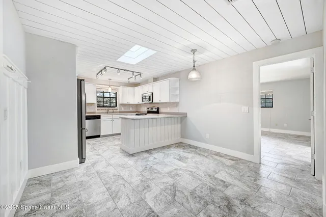 a kitchen with stainless steel appliances kitchen island a refrigerator sink and cabinets